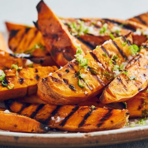 Grilled sweet potato wedges garnished with lime zest and sea salt on a plate