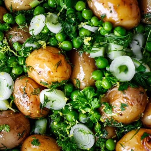A bowl of buttered baby potatoes mixed with dill, peas, and spring onions.