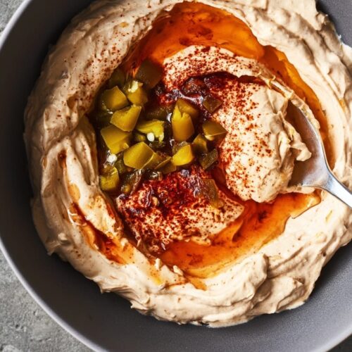 A bowl of creamy dip topped with jalape&ntilde;os and a drizzle of honey.