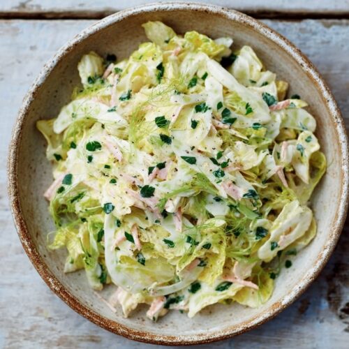 A bowl of coleslaw salad featuring shredded cabbage, herbs, and a creamy dressing.