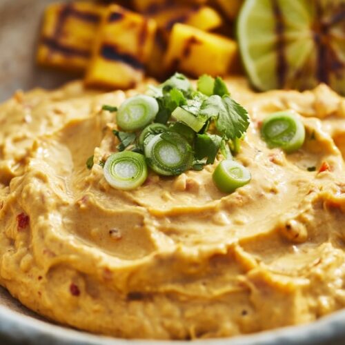 Creamy mango habanero dip garnished with green onions, served with grilled lime and pineapple.