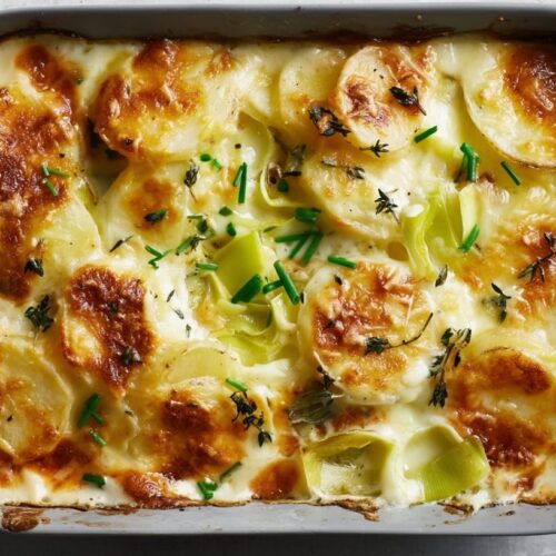 Baked potato gratin with layers of potatoes, leeks, and a golden cheese crust on top.